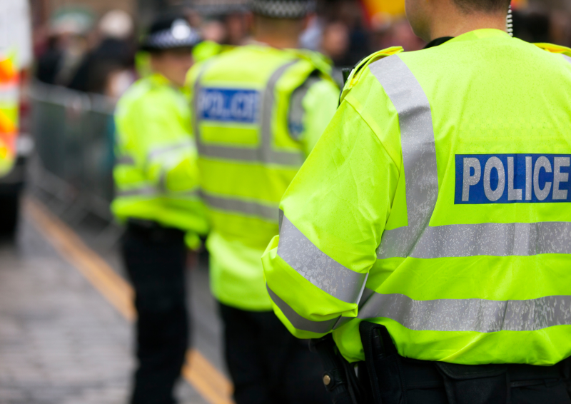 Police officers line up on a busy street filled surrounded by barrier fencing 